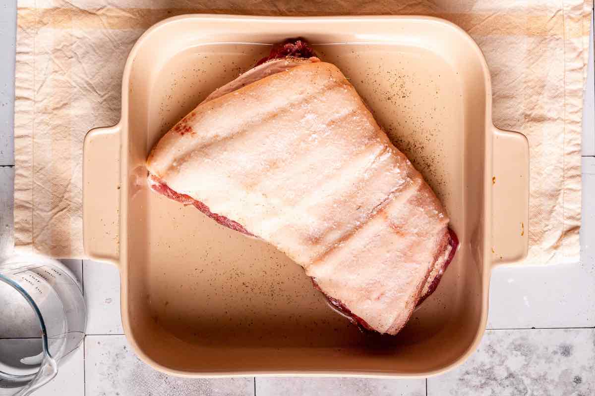 seasoned raw pork belly in a baking dish.